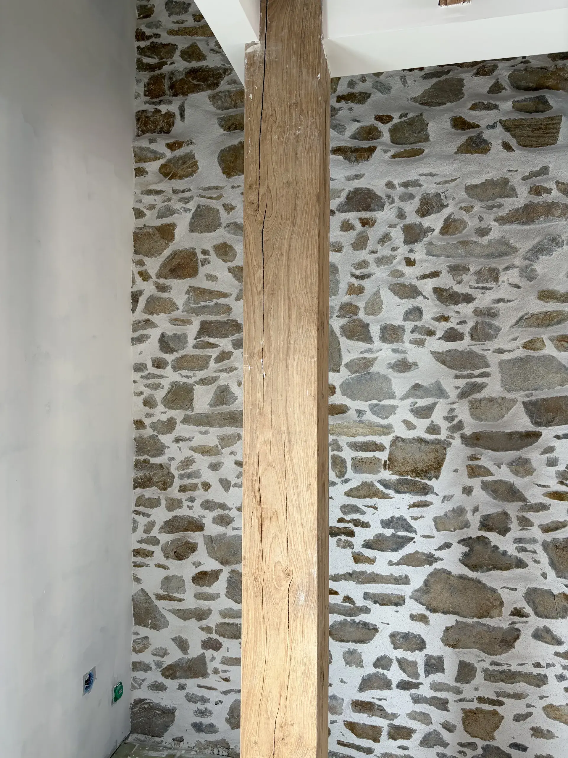 Mur intérieur en pierre apparente et poutre restaurés