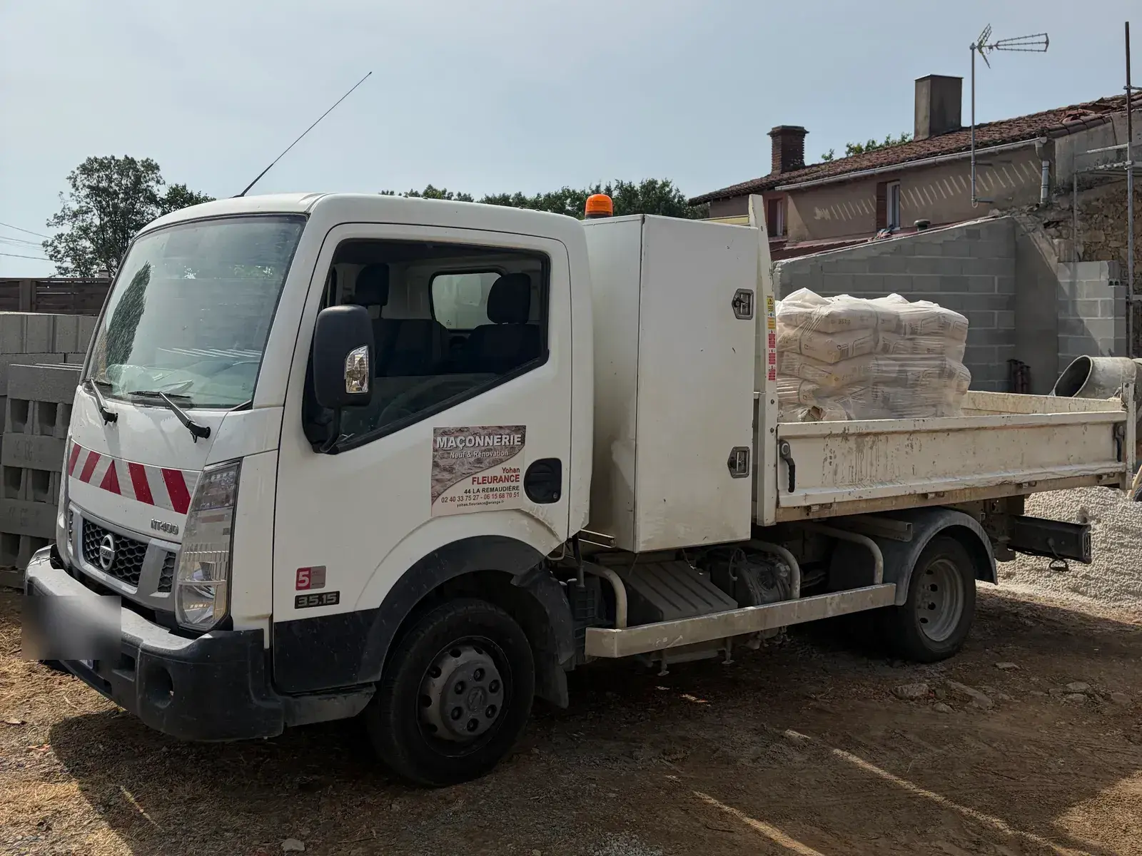 Camion benne Fleurance Maçonnerie chargé de sacs de mortier sur un chantier