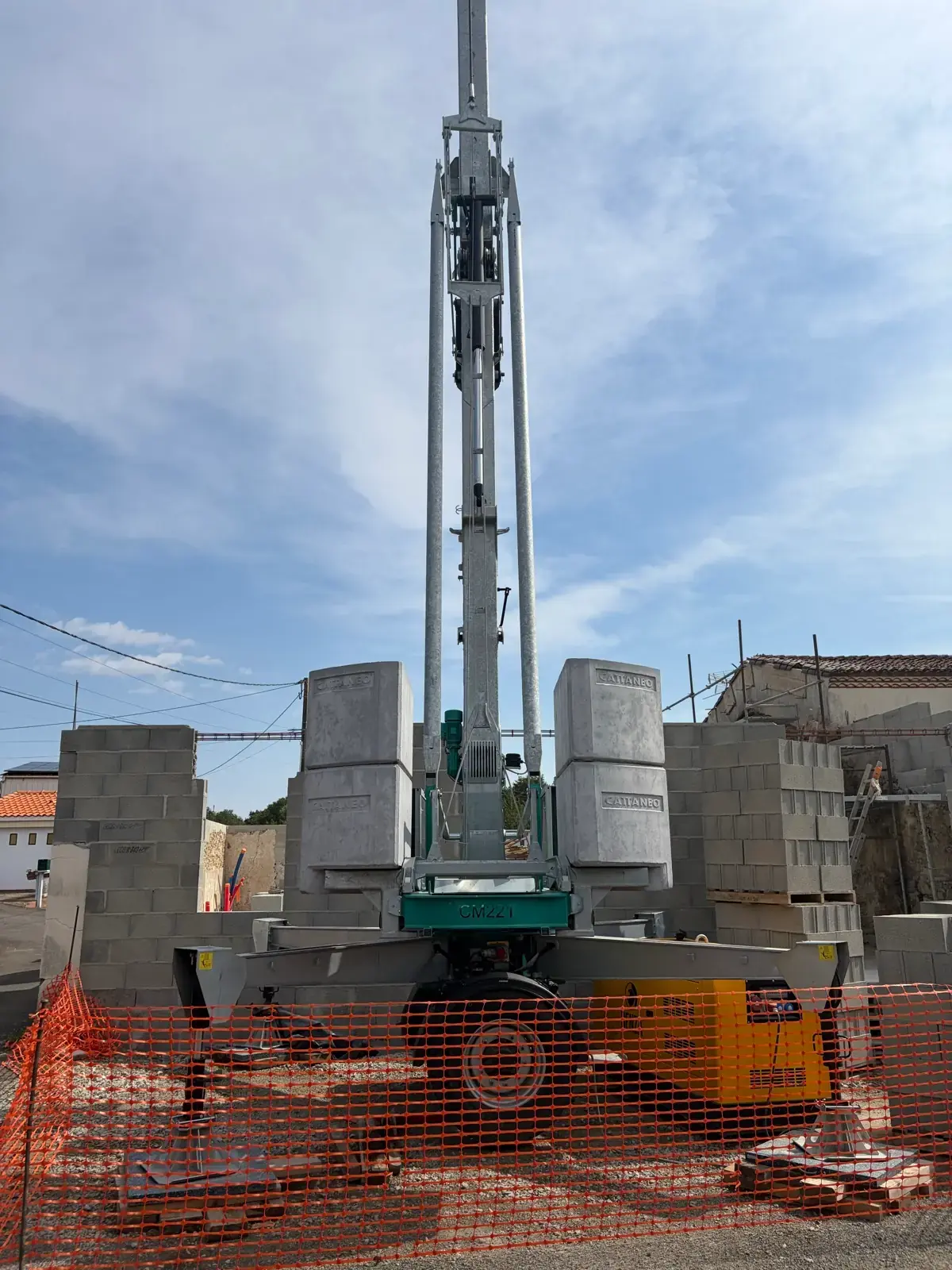 Grue automontante dressée entre les palettes de parpaings, murs neufs en arrière-plan