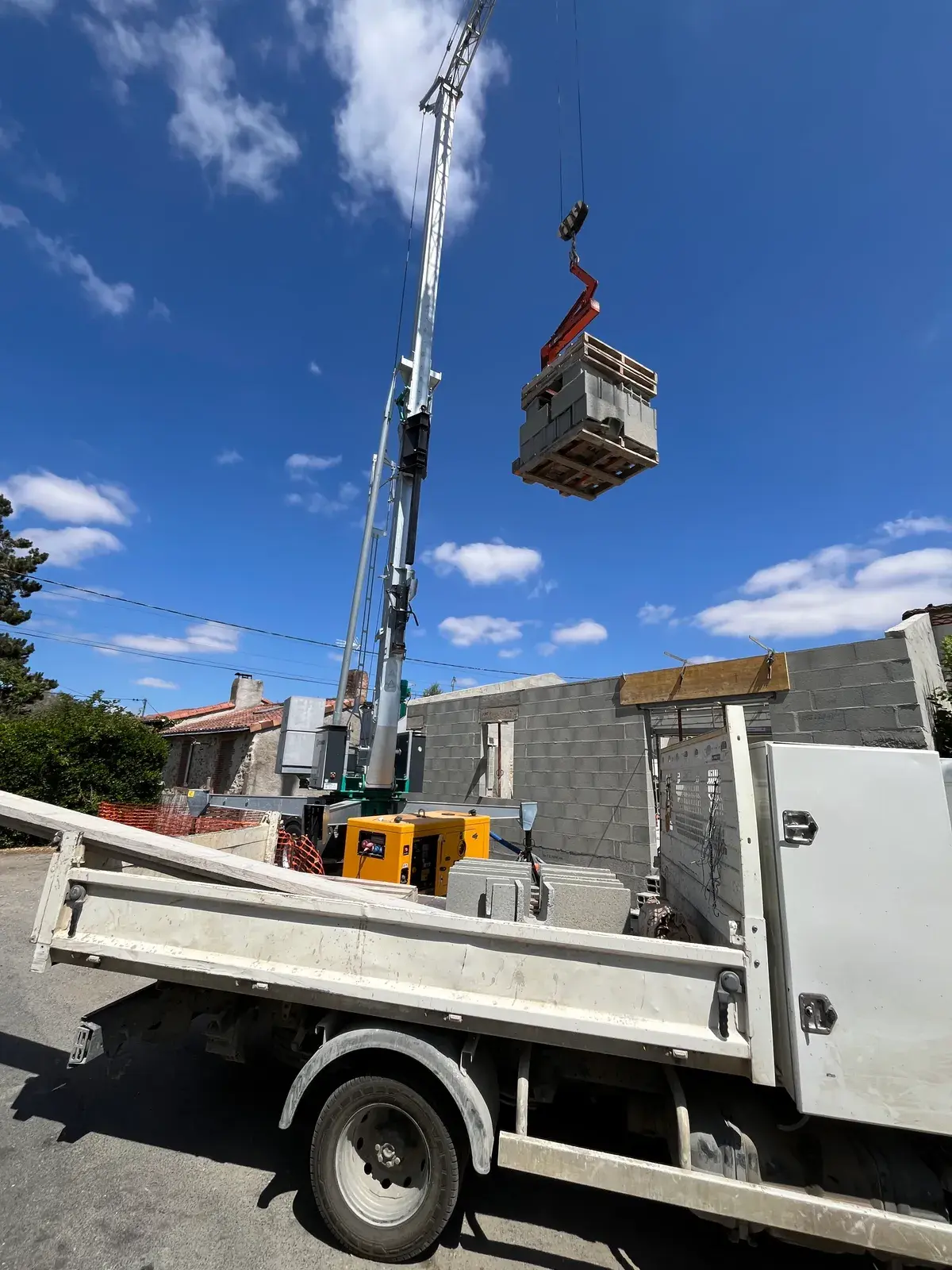 Palette de parpaings suspendue à la grue au-dessus du camion benne Fleurance Maçonnerie