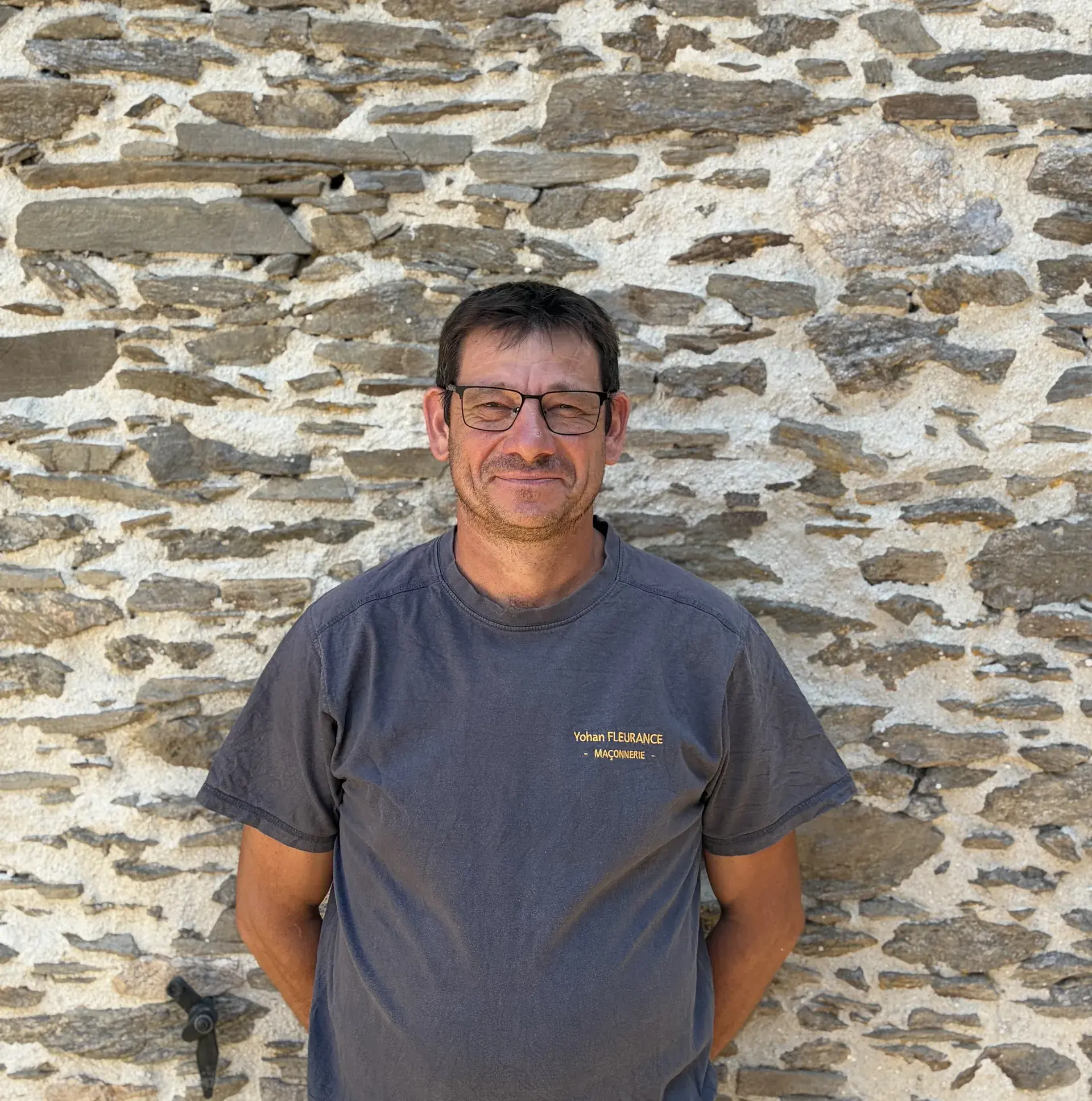 Yohan Fleurance, gérant de Fleurance Maçonnerie, devant un mur en pierre